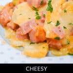 A delicious close-up of a cheesy ham and potato casserole topped with chopped parsley, served invitingly on a white plate.