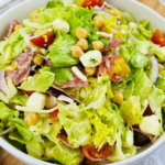 An Italian Chopped Salad featuring tomatoes, lettuce, and chickpeas in a white bowl.