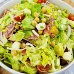 An Italian Chopped Salad featuring tomatoes, lettuce, and chickpeas in a white bowl.