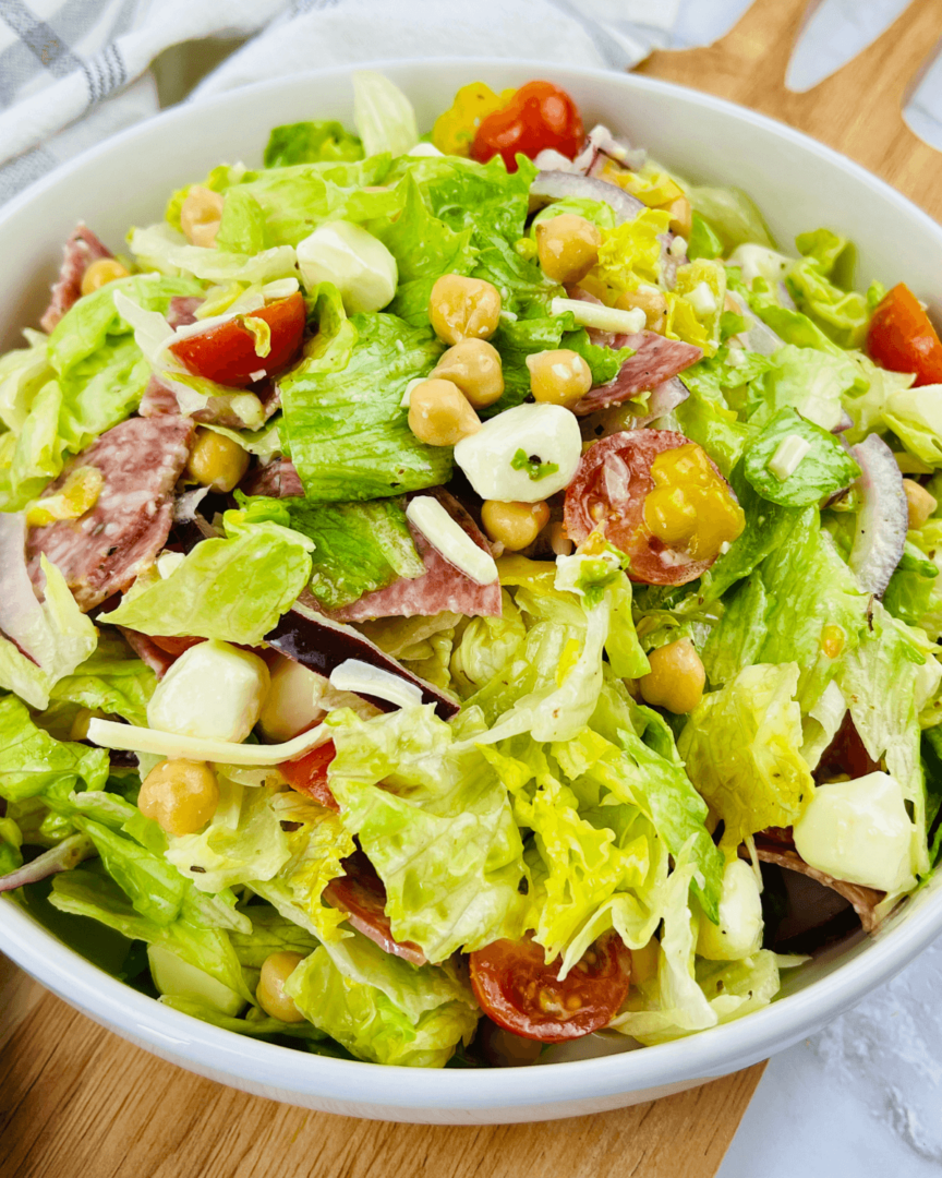 An Italian Chopped Salad featuring tomatoes, lettuce, and chickpeas in a white bowl.