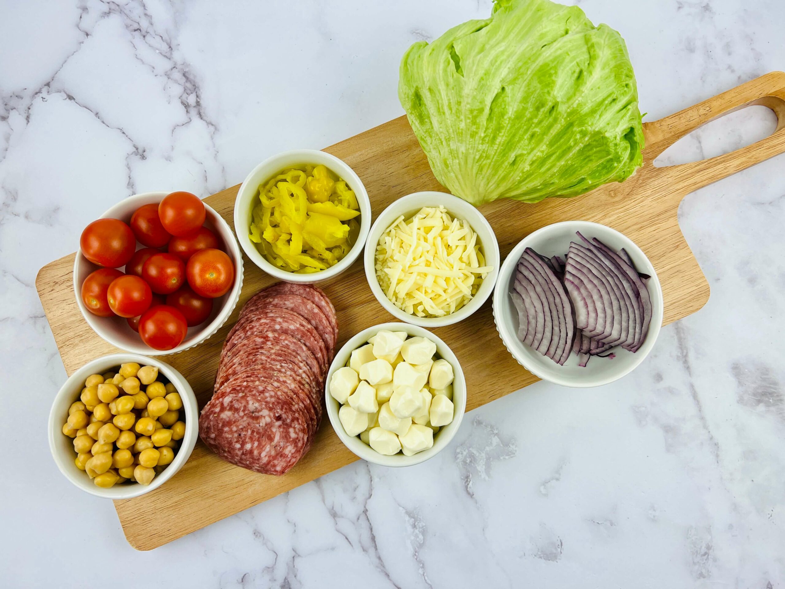 A cutting board with ingredients, including meat, vegetables, and chickpeas.