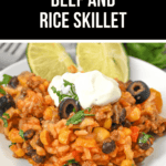 Mexican Beef and Rice Skillet featuring corn, black olives, and cheese, all topped with a dollop of sour cream and garnished with fresh lime wedges for vibrant flavor.