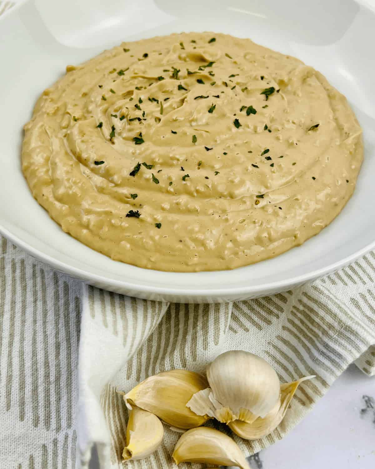 A white dish of the roasted garlic aioli.
