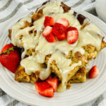A plate of bread pudding topped with vanilla glaze and fresh strawberries.