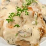 Creamy mushroom sauce over pork chops garnished with fresh herbs.