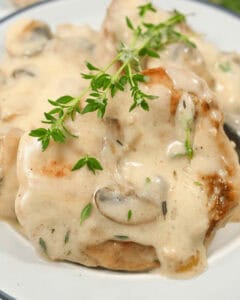 Creamy mushroom sauce over pork chops garnished with fresh herbs.