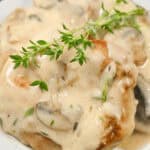 Creamy mushroom gravy drizzled over pork chops, garnished with fresh herbs.