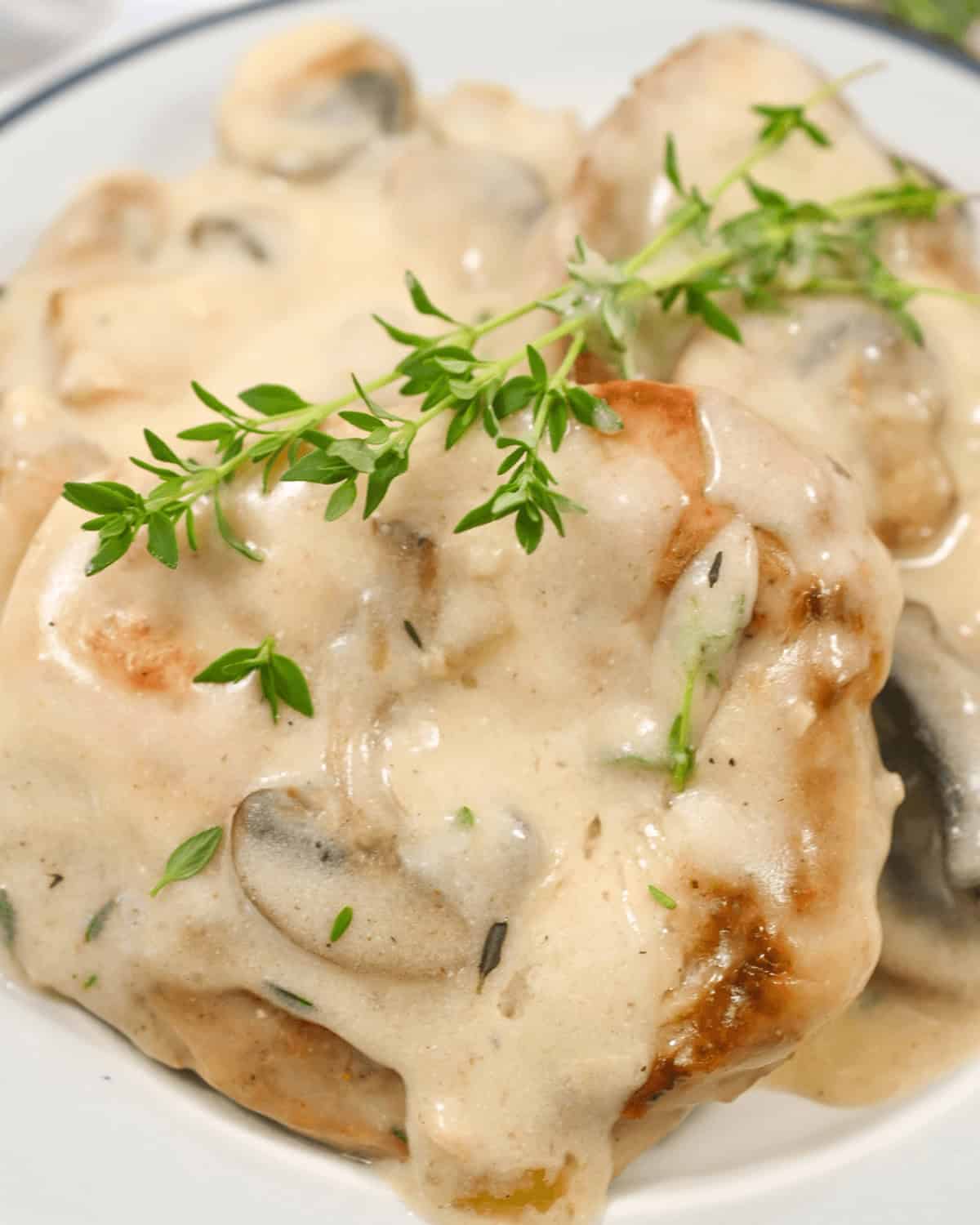 Creamy mushroom gravy drizzled over pork chops, garnished with fresh herbs.