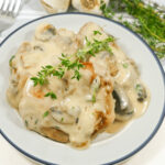 Pork chops with a creamy mushroom sauce garnished with fresh herbs served on a plate.