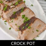 Slow-cooked pork tenderloin in a crock pot, sliced and drizzled with balsamic glaze, is elegantly garnished with chopped parsley on a pristine white plate.