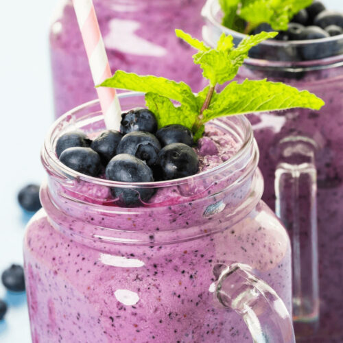Blueberry pineapple smoothie in mason jars with mint leaves.