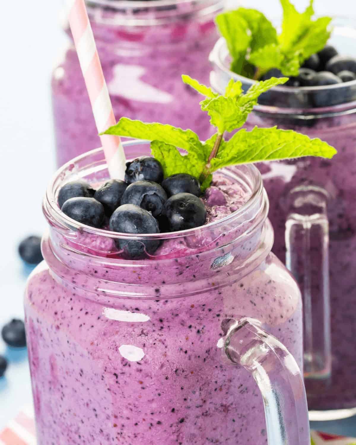 Blueberry pineapple smoothie in mason jars with mint leaves.