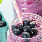 A refreshing blueberry smoothie in a jar with a straw.