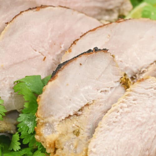 Slices of Cuban mojo pork on a white serving tray.