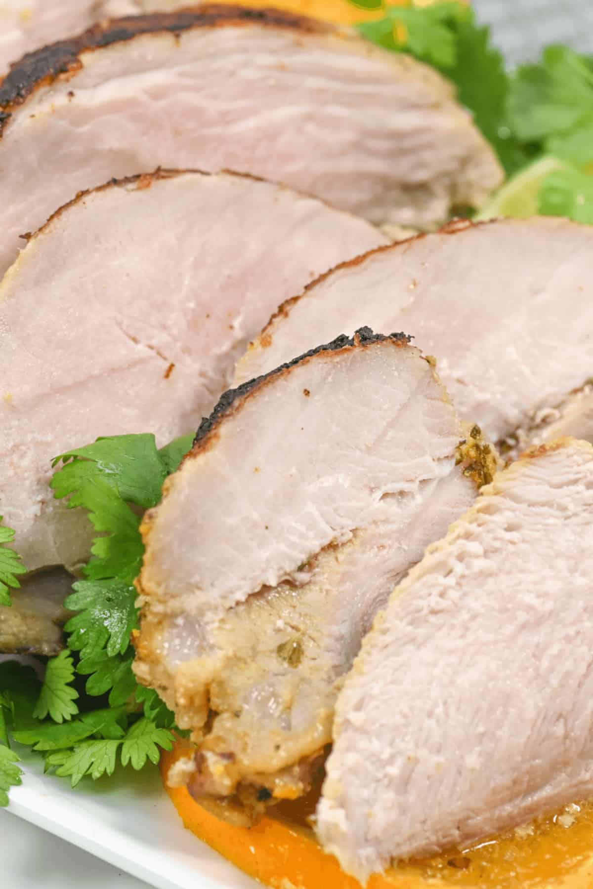 Slices of Cuban mojo pork on a white serving tray.