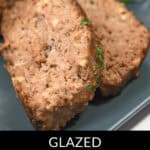 A close-up of succulent BBQ meatloaf slices on a plate, glistening with glaze and garnished with fresh herbs.