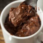 A spoonful of chocolate chip mug cake is lifted from a white mug.