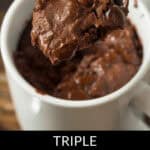 A spoon lifts a bite of chocolate chip mug cake from a white mug. The chocolate chip mug cake is rich and gooey, topped with melted chocolate chips.