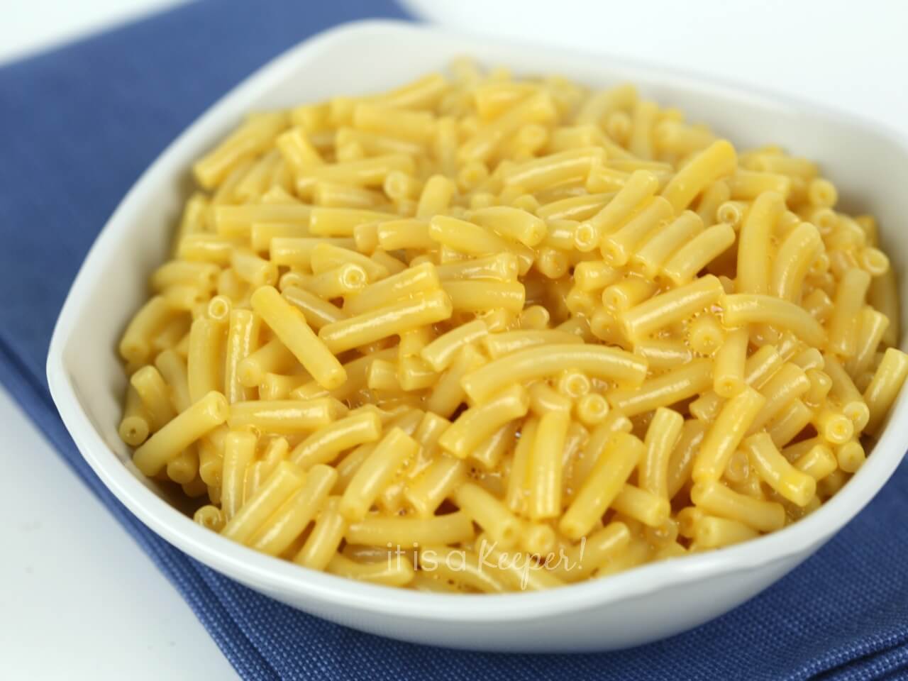 mac and cheese in white bowl on a blue napkin. 