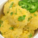 A bowl of creamy corn cakes garnished with fresh parsley and sliced jalapeños, inspired by the flavors of Mexican Corn Cake.