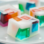 A mosaic of colorful jelly cubes on a white plate.