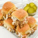 A stack of sandwiches on a tray with a slide of pickles.