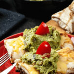 A plate of beef enchiladas served with a side of guacamole, showcased beautifully on a vibrant red plate.
