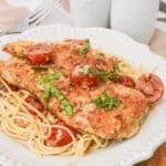A white plate with chicken margherita on it.