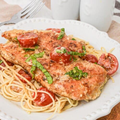 A white plate with chicken margherita on it.