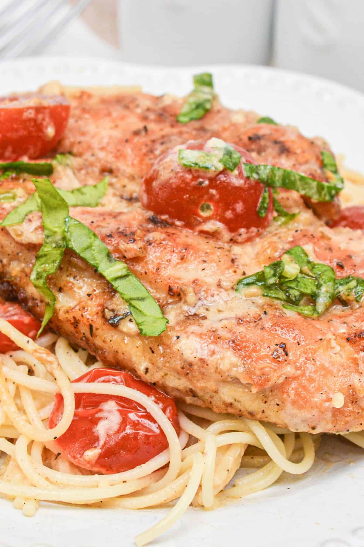 Chicken margherita over spaghetti.