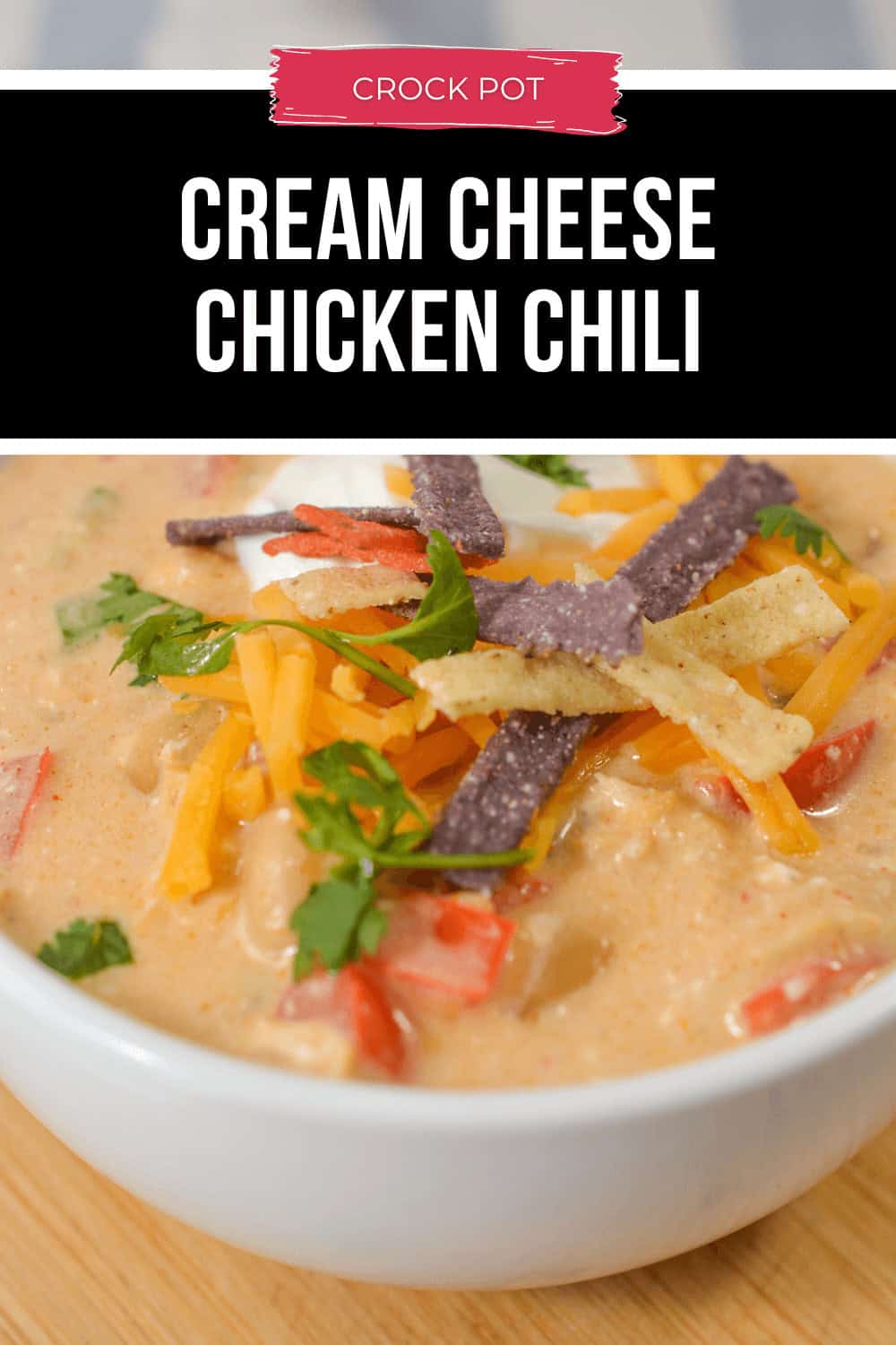 A close-up of a bowl of creamy Cream Cheese Chicken Chili, garnished with shredded cheese, crunchy tortilla strips, and fresh cilantro.