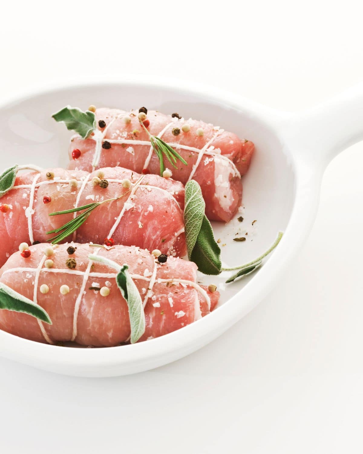 An authentic Italian Braciole dish featuring a succulent cut of meat and aromatic herbs beautifully presented on a simple white plate.