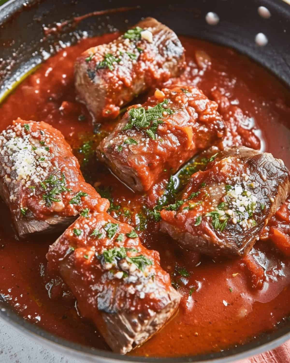 Italian braciole in tomato sauce cooked in a skillet.