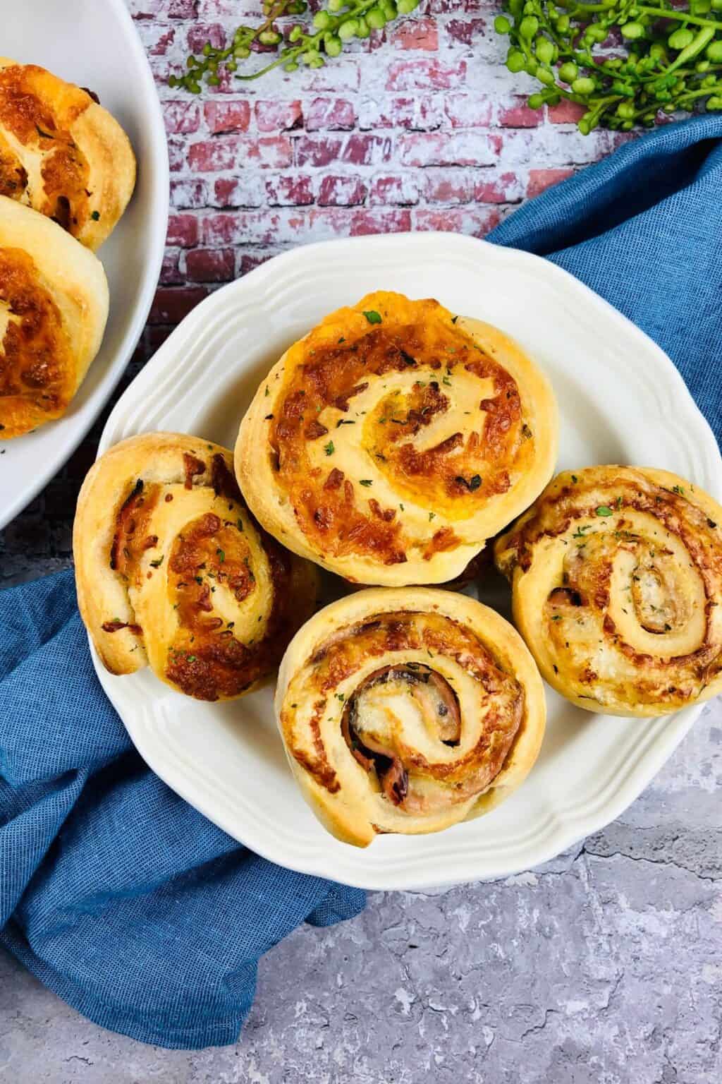 A white plate with five golden brown garnished with herbs, sits on a blue cloth atop a stone surface.