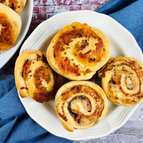 A white plate with five golden brown garnished with herbs, sits on a blue cloth atop a stone surface.
