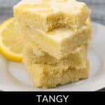 A tempting stack of three lemon brownies with glaze sits elegantly on a plate, beautifully garnished with fresh lemon slices.