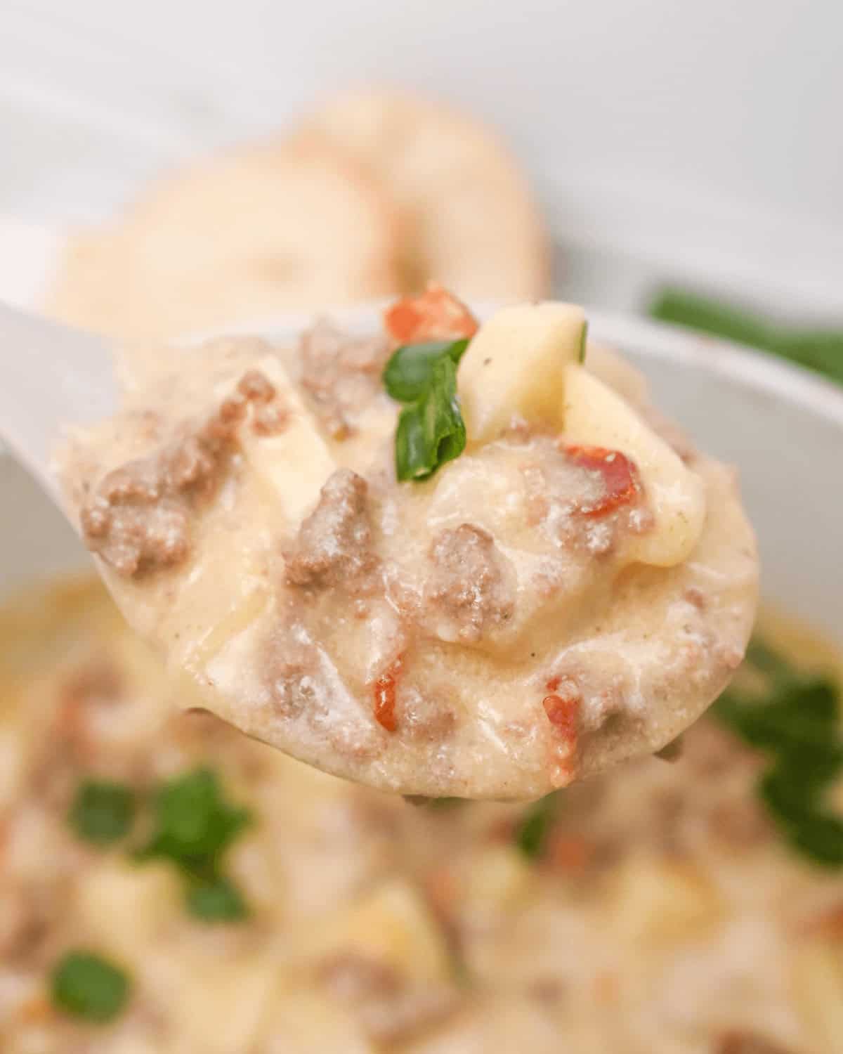 A cheesy potato soup with a spoonful of hamburger.