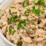 A bowl of creamy chipotle chicken salad garnished with fresh herbs.