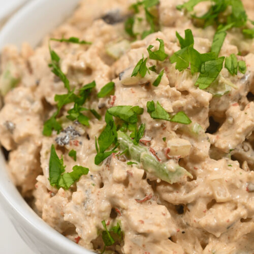 A bowl of creamy chipotle chicken salad garnished with fresh herbs.