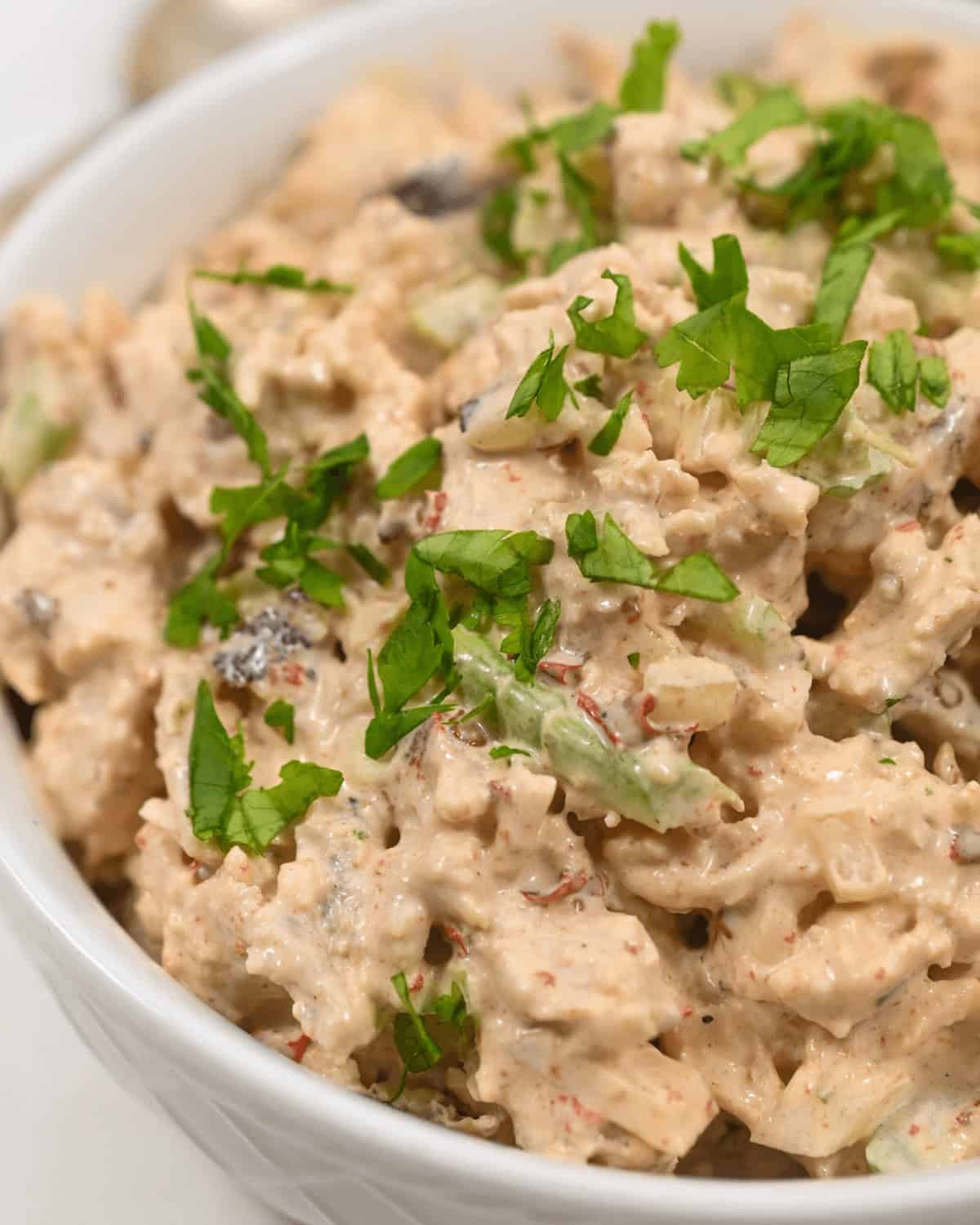 A bowl of creamy chipotle chicken salad garnished with fresh herbs.