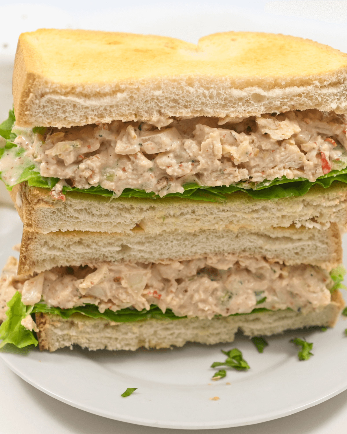 A multi-layered chipotle chicken salad sandwich with lettuce on white bread.