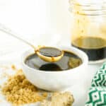 A spoon drizzles sauce in the jar.