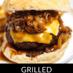 A Whiskey Burger with Jack Daniels whisky sauce, melted cheese, caramelized onions, and a side of fries on a sesame seed bun. Text: "Grilled Jack Daniels Whisky Burger".
