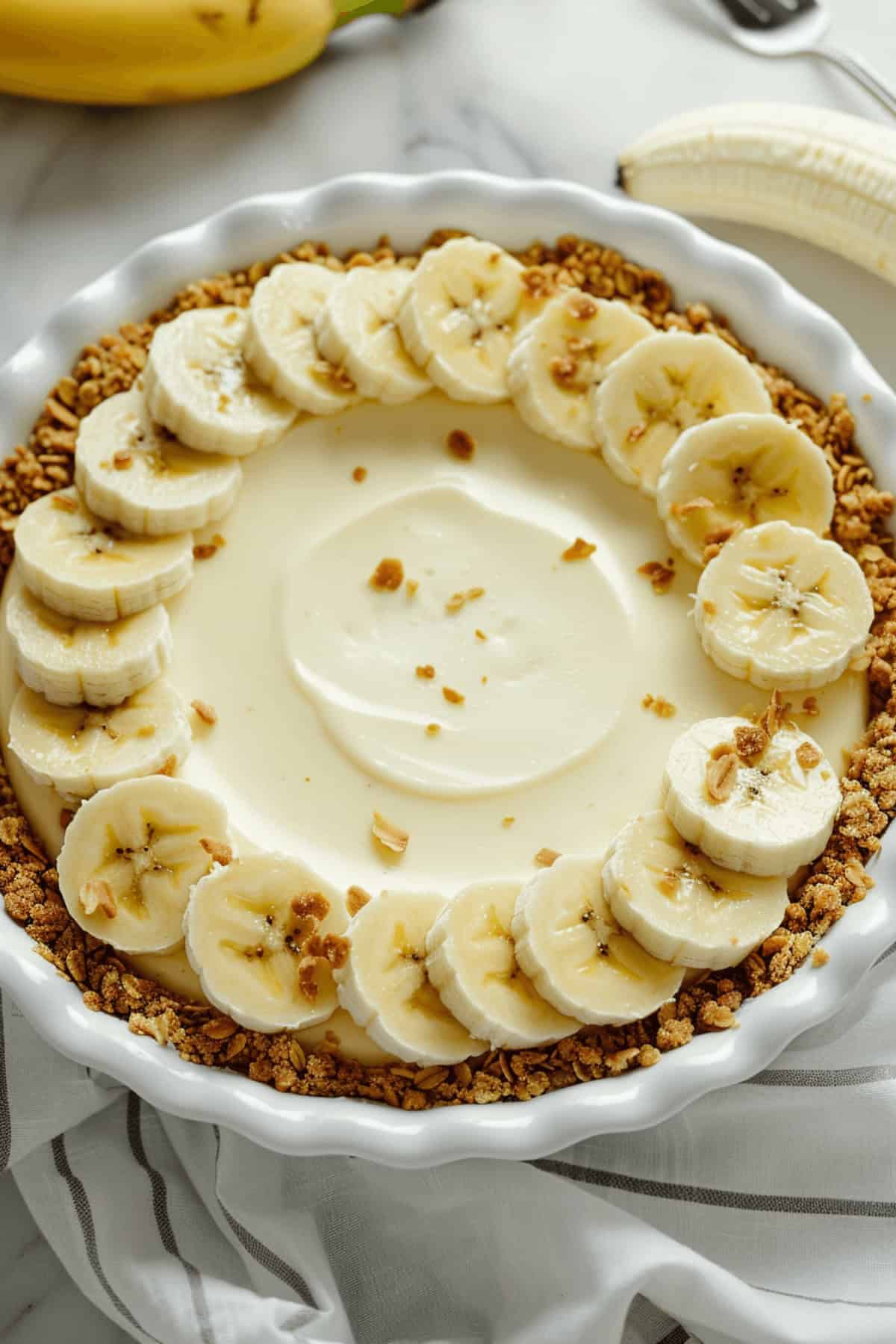 A banana cheesecake surrounded by slices of banana.