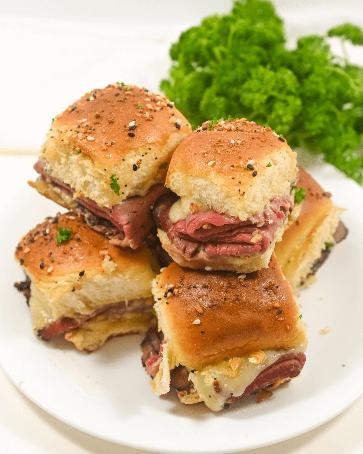 A plate of roast beef sliders with meat and cheese and Dijon sauce.