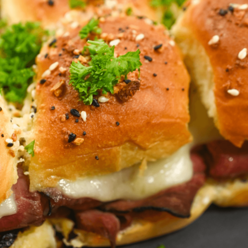A close up of roast beef sliders with Dijon sauce.