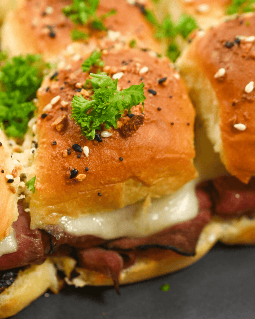 A close up of roast beef sliders with Dijon sauce.