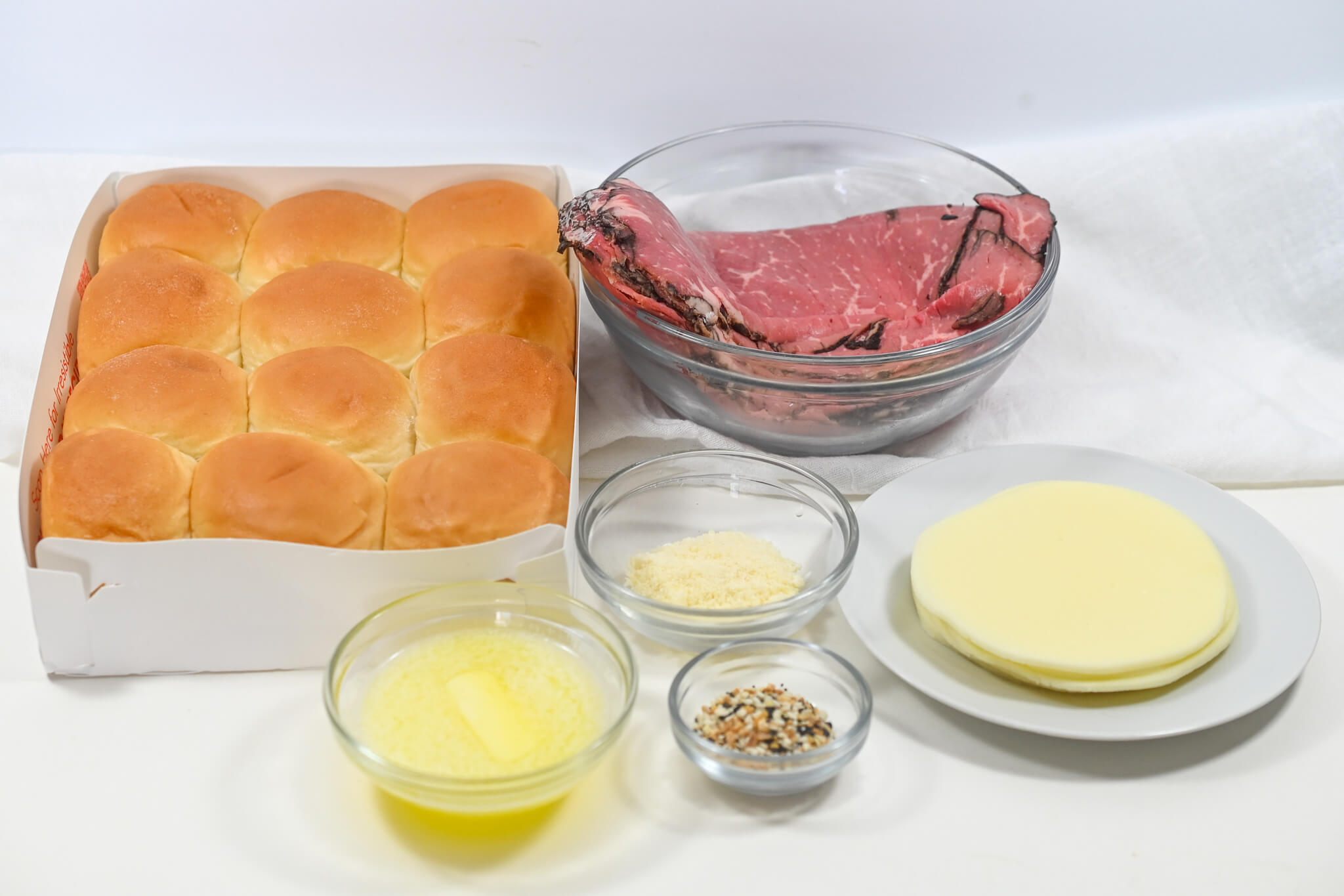 A table with roast beef sliders and ingredients.