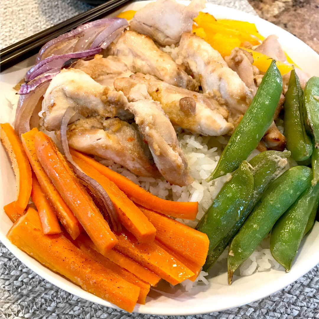 Best korean chicken over rice with a side of vegetables and carrots. 