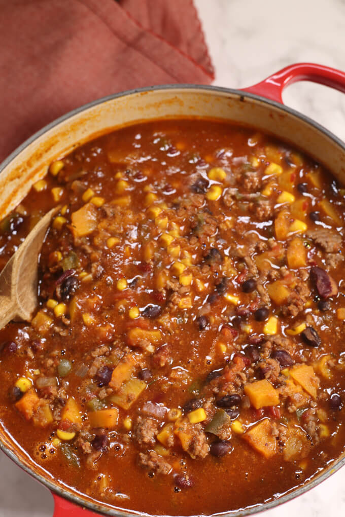 Chili in a large pot with a wooden spoon